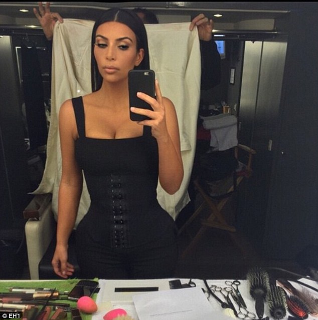 Kim Kardashian wearing a black waist trainer and taking a mirror selfie showing off her curves